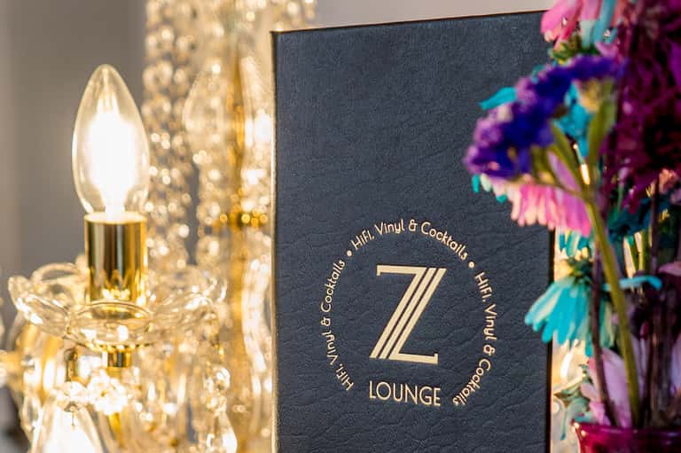 Z Lounge sign with gold accents, crystal lamp, and colorful flowers for cocktails and vinyl