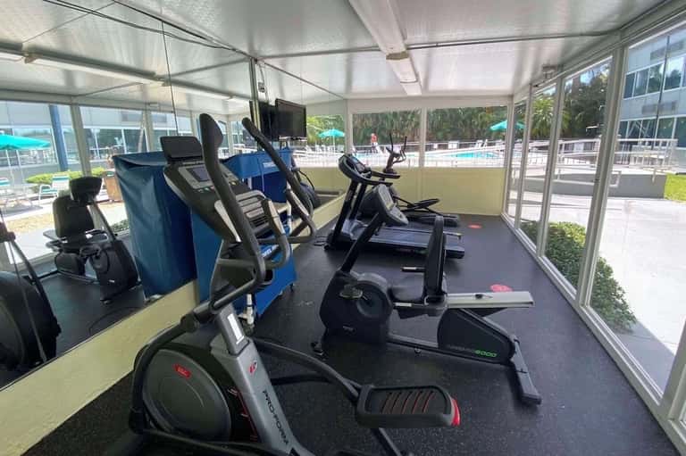 Modern fitness center with exercise bikes and elliptical machines in a bright glass-enclosed room