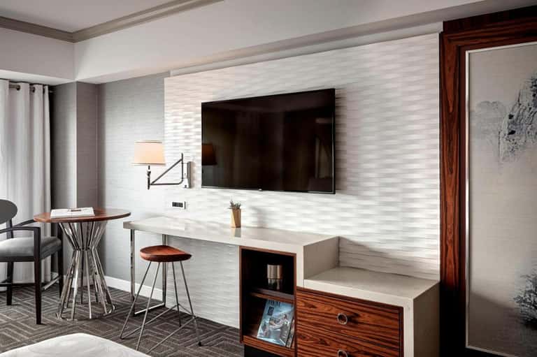 Hotel room with flat-screen TV, desk area, wooden accents, and modern furnishings