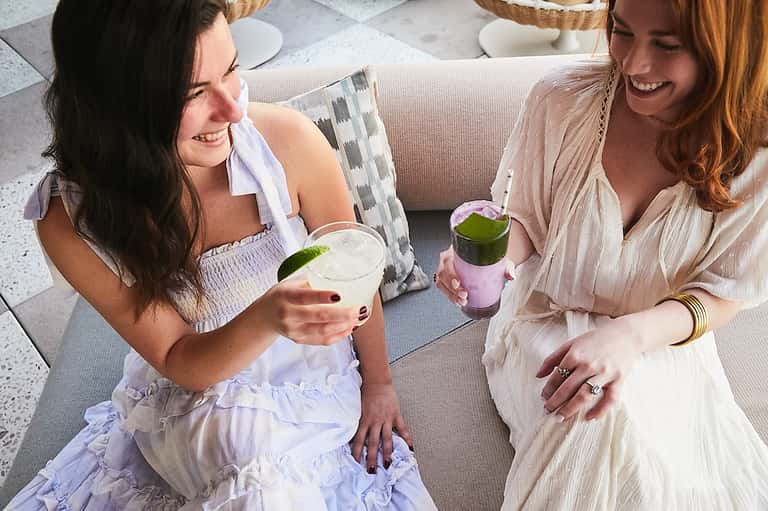 Two women enjoying cocktails on lounge chairs at upscale resort terrace