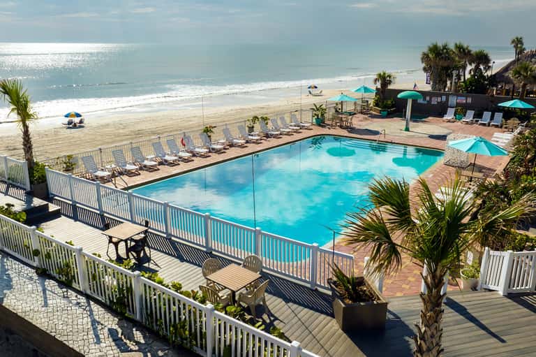 Beachfront resort pool with umbrellas and ocean view