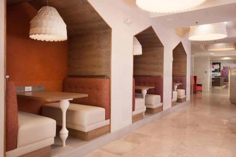 Modern spa lounge with booth seating, pendant lighting, and warm orange accent walls