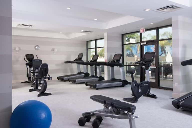 Bright fitness facility with treadmills, stationary bikes, exercise ball, and glass doors