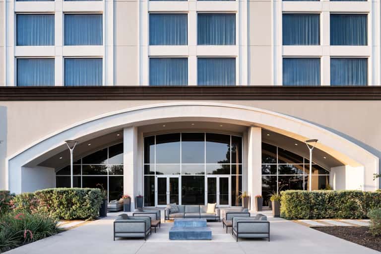 Contemporary hotel exterior entrance with curved architecture, glass doors, and modern lounge seating