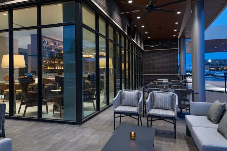 Modern rooftop lounge at dusk with striped seating, large windows, and city skyline views