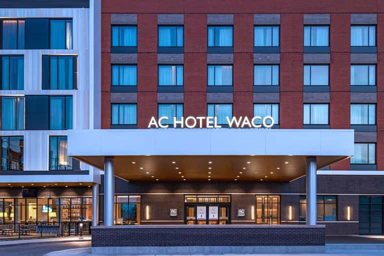 AC Hotel Waco brick building facade with illuminated entrance at dusk