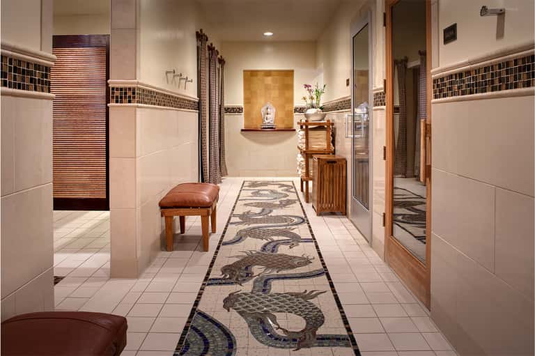 Spa corridor with decorative mosaic floor featuring fish patterns, tiled walls, and wooden accents