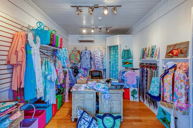 Retail boutique interior with colorful beachwear displayed on walls and clothing racks