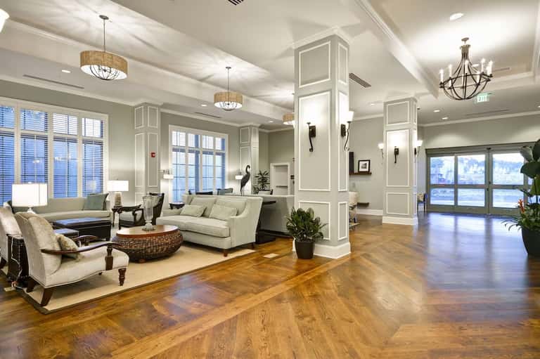 Elegant hotel lobby with hardwood floors, cream seating, chandeliers, and waterfront views