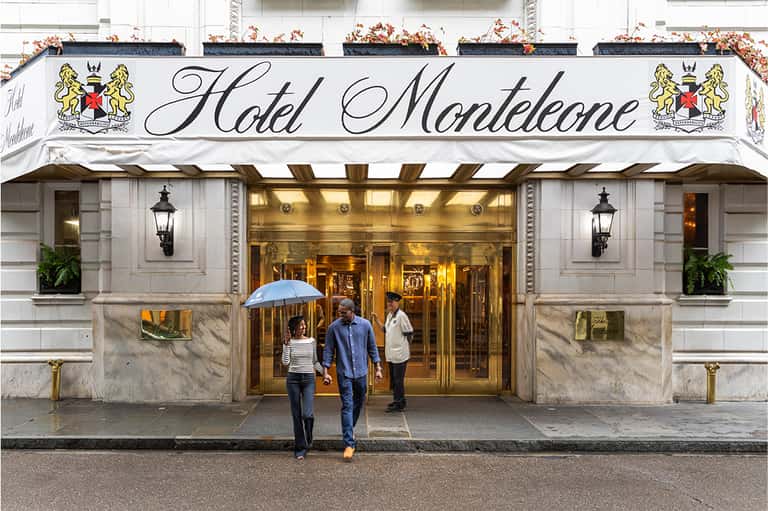 Hotel Montelcone entrance with elegant white awning, brass fixtures, and guests with umbrella on rainy street