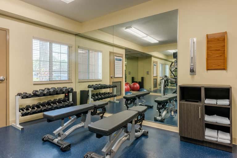 Modern fitness center with dumbbells, weight benches, mirrors, and exercise equipment