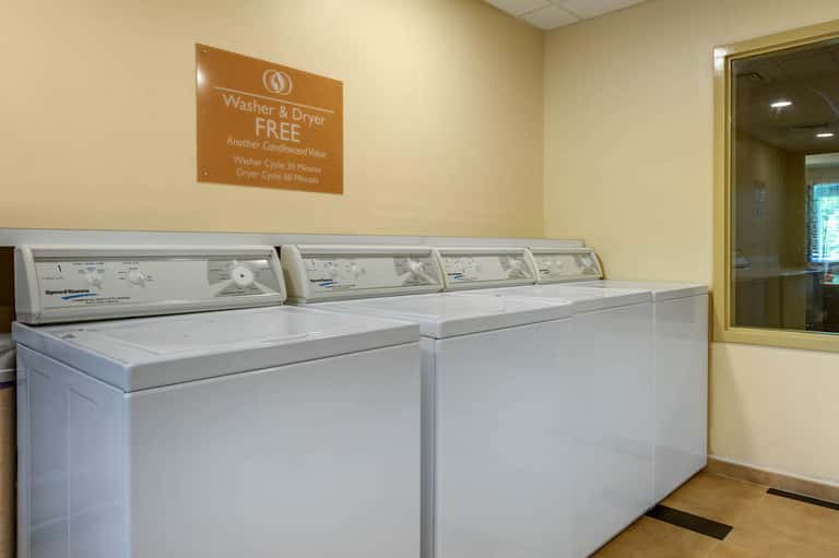 Laundry facility with white washers and dryers, orange sign advertising free service