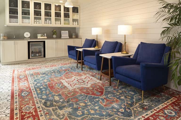 Spa lounge with navy chairs, ambient lighting, and display shelving for wellness products