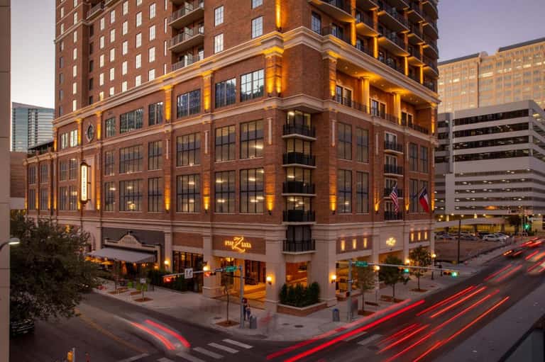 Historic brick building illuminated at dusk with ground-floor retail in urban downtown setting