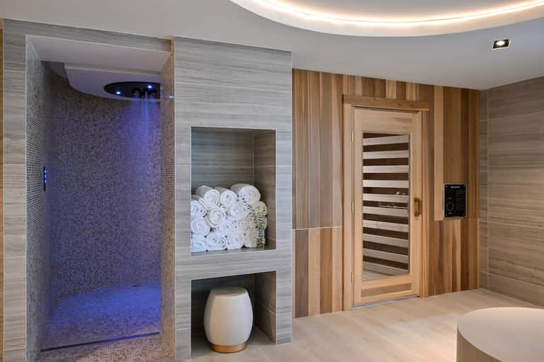 Luxury spa facility with steam shower featuring blue lighting and sauna room