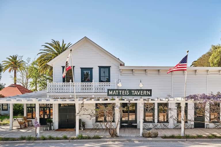 Historic white Matteis Tavern building with American flag and covered porch