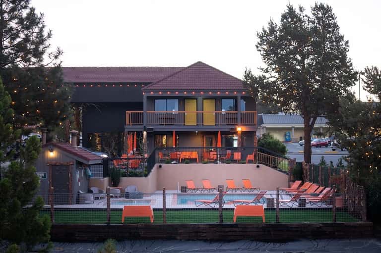 Lakeside resort with orange chair seating, evening lights, and multi-story lodge building