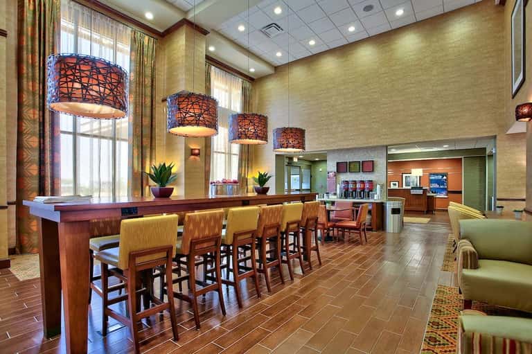 Hotel lobby bar and lounge with decorative pendant lights, wood accents, and comfortable seating areas