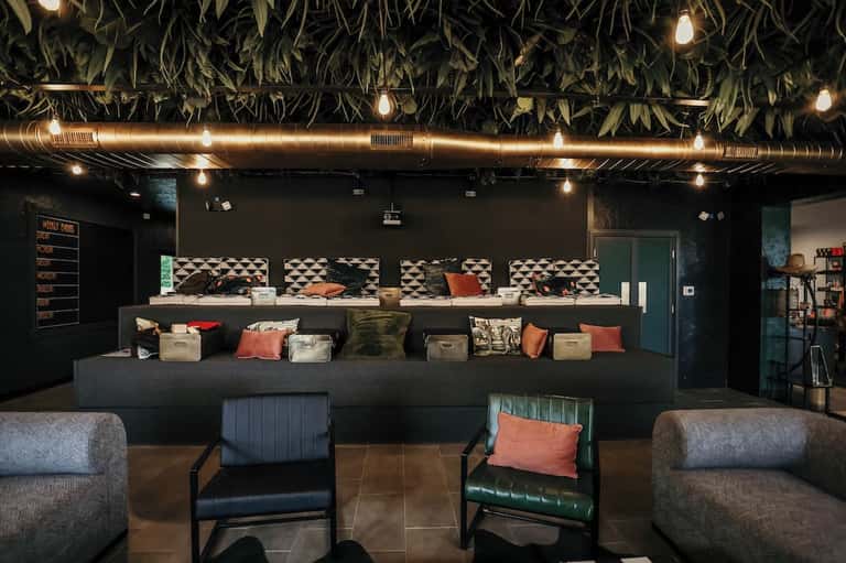 Modern hotel reception desk with black walls, geometric patterns, decorative pillows, and contemporary seating