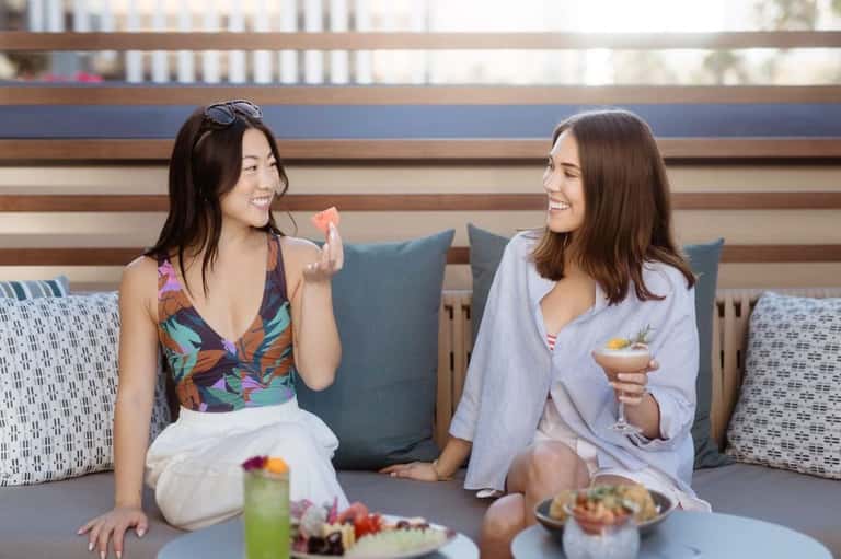 Two women enjoying drinks and appetizers at casual lounge seating area
