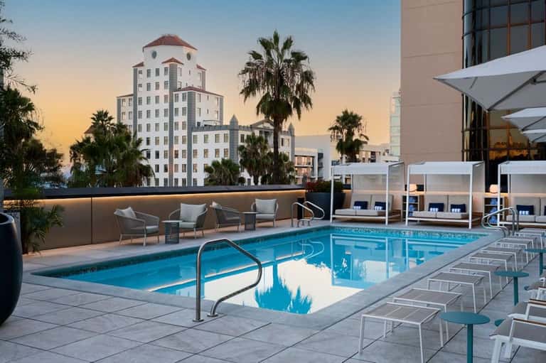 Sunset pool view with historic building, palm trees, and white umbrellas on deck