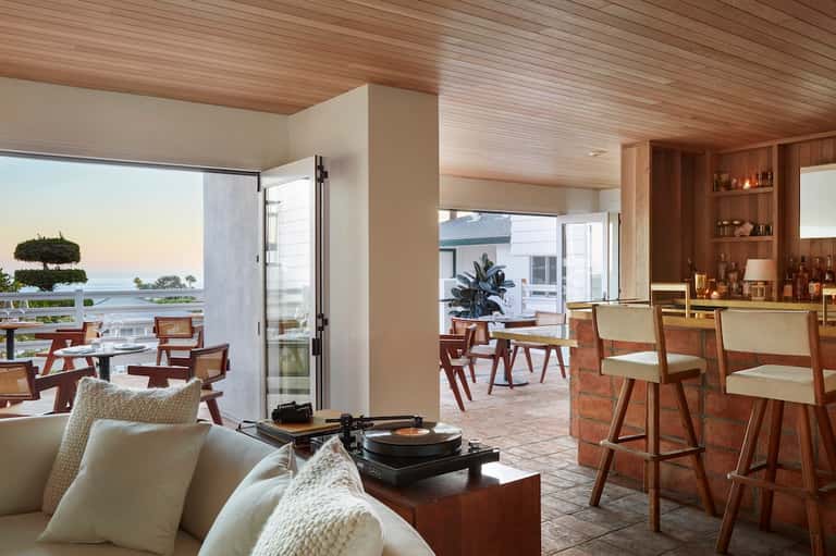 Coastal lounge area with ocean views, modern furniture, wooden elements, and bar seating by windows