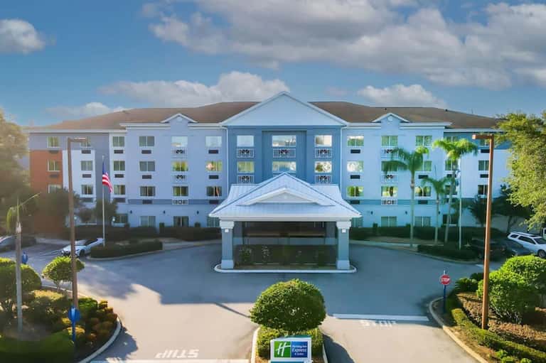 Blue and white multi-story hotel building with covered entrance and manicured grounds