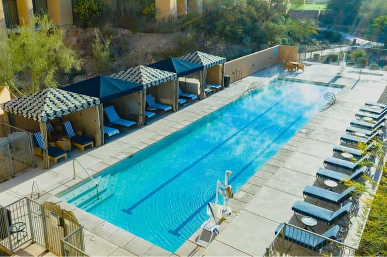 Aerial view of lap pool with private cabanas and lounge chairs by the water