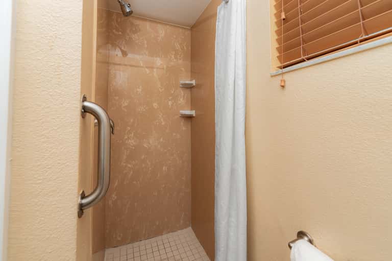Clean bathroom with walk-in shower, grab bars, and neutral tile and wall finishes