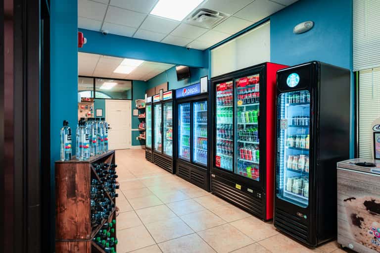 Convenience store interior with turquoise walls and multiple refrigerated beverage vending machines