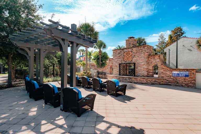 Outdoor lounge area with black and blue chairs under pergola near resort pool