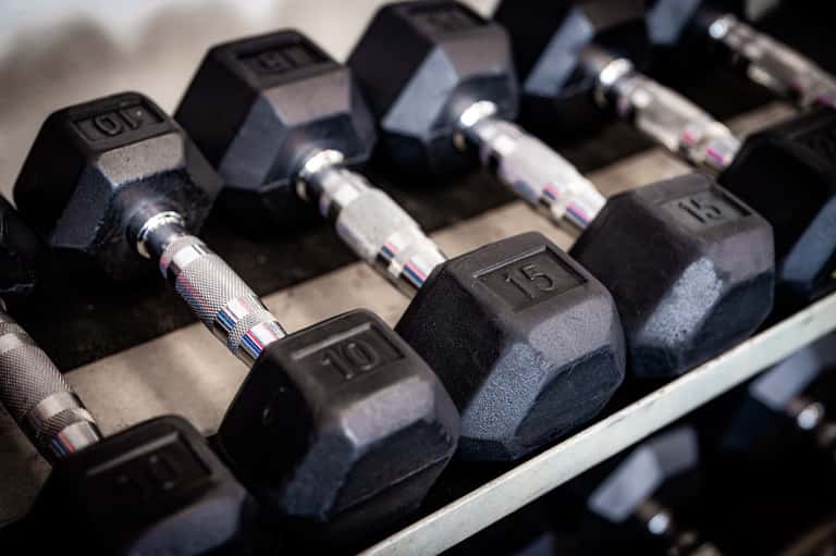 Close-up of dumbbells on a rack in a gym, numbered weights displayed