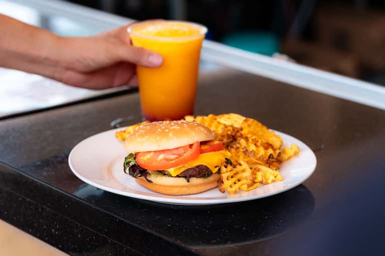 Cheeseburger with waffle fries and orange juice on a black hotel dining table