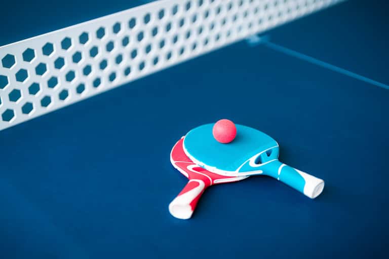 Colorful ping pong paddle and ball on blue table with net