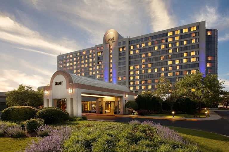 Hyatt hotel entrance with illuminated signage, modern white portico, and multi-story building at twilight