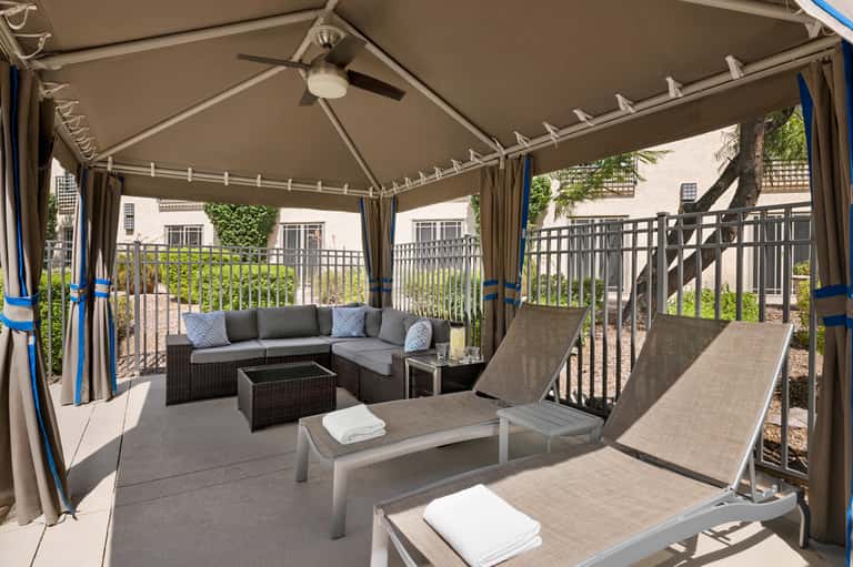 Covered patio lounge area with gray sectional sofa and lounge chairs under pergola