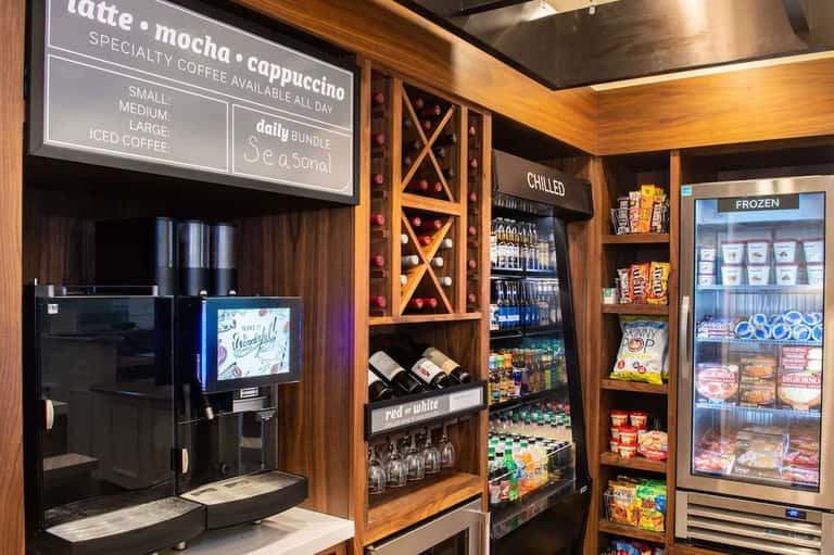 Coffee bar with specialty beverages menu, espresso machine, and refrigerated snacks display