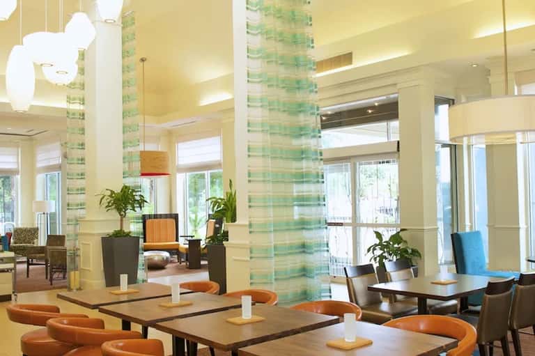 Bright hotel lobby with green tile columns, orange accents, and modern furnishings