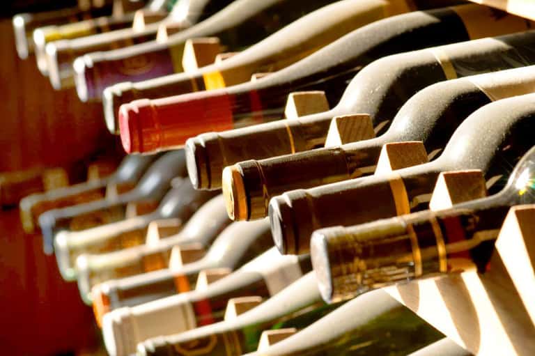 Wine bottles arranged in a cellar rack displaying various red and white wines