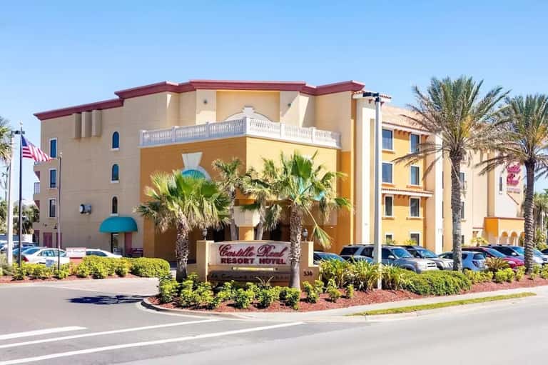 Colorful Mediterranean-style hotel exterior with palm trees and curved architecture