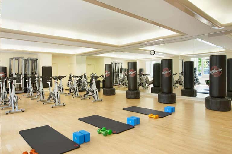 Fitness center with stationary bikes, punching bags, weights, and wooden flooring