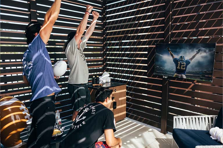 Recreation room with slatted wood walls, TV, and people celebrating