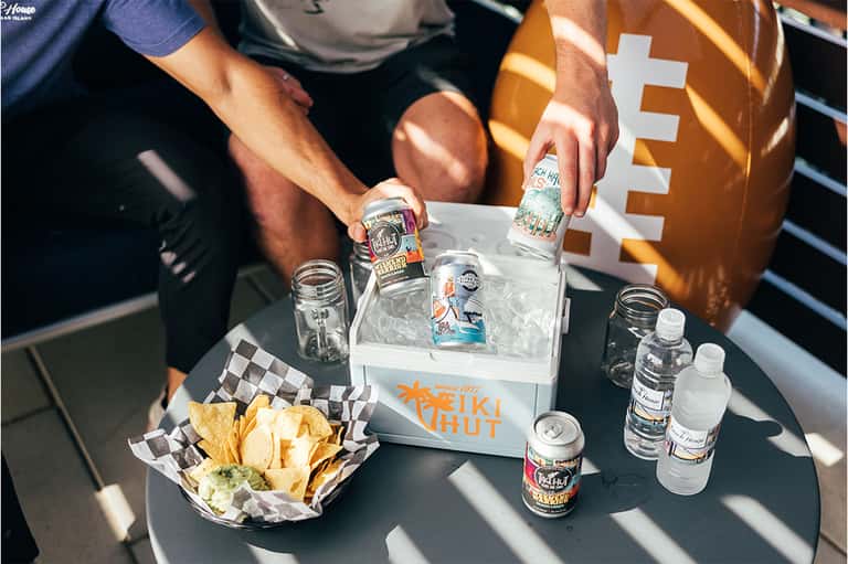 Poolside beverage service with cooler, snacks, and tropical drinks on low table