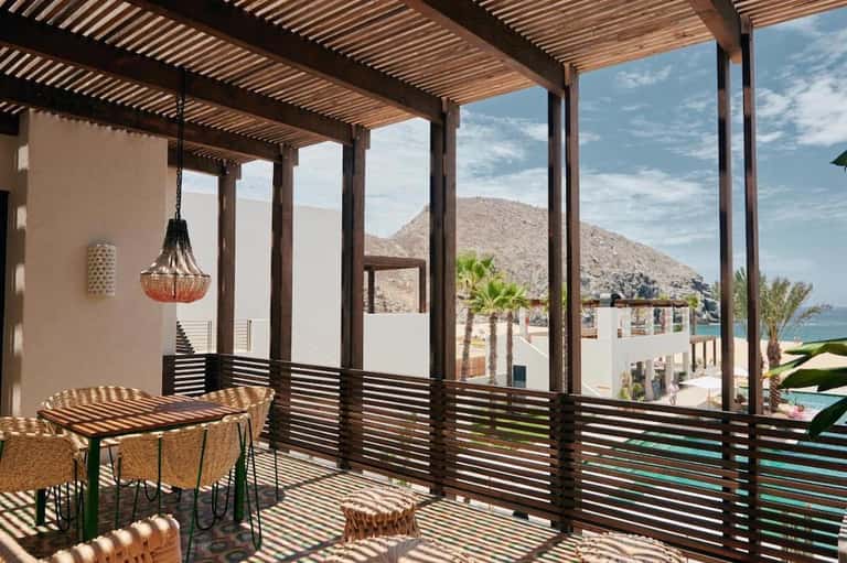 Luxury terrace with wooden pergola, mountain and ocean views, dining table, and modern railings
