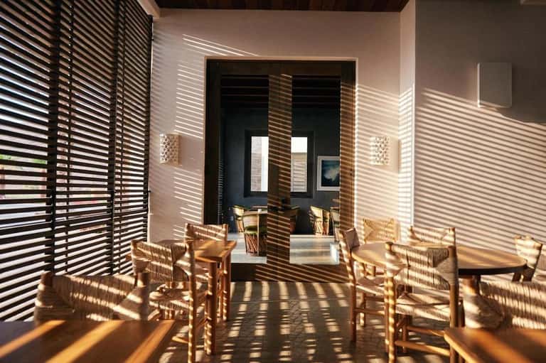 Covered outdoor patio with black louvered screens casting striped shadows on white walls