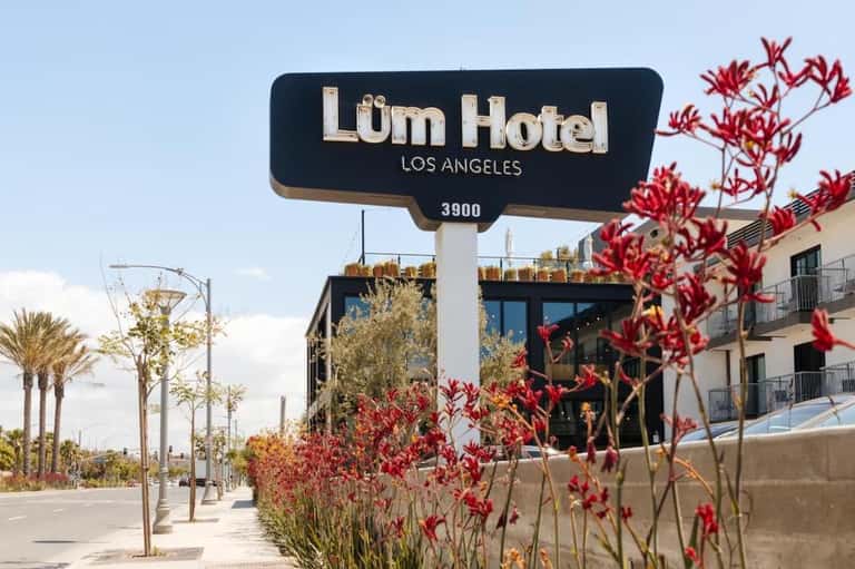 Lüm Hotel Los Angeles exterior signage with red flowers and palm trees on Wilshire Boulevard