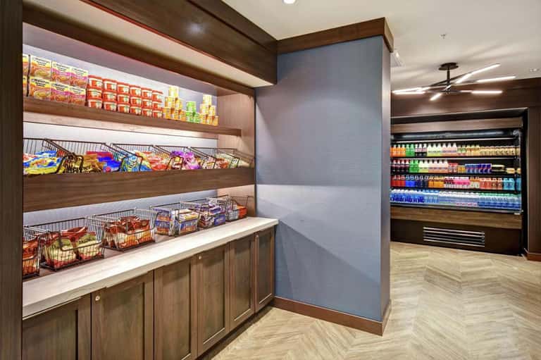 Hotel convenience store with wooden shelving displaying snacks, beverages, and packaged goods