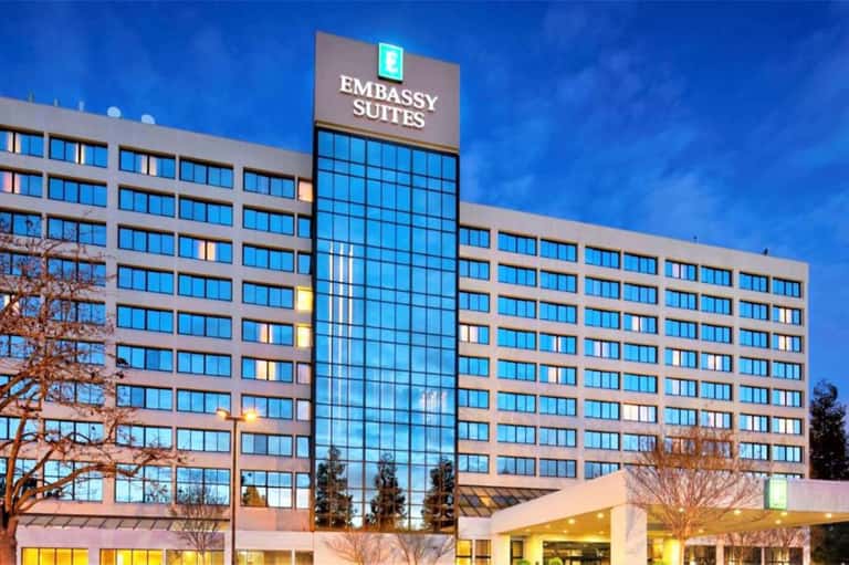 Modern Embassy Suites hotel building facade at dusk with illuminated windows