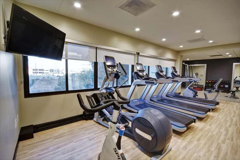 Indoor fitness center with treadmills and stationary bikes facing large windows with mountain views