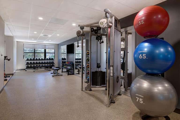 Fitness center with exercise equipment, dumbbells, medicine balls, and cable machines on carpeted floor